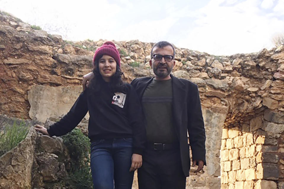 In this March 12, 2020 photo made available by Reem Mousa, Ismail Mousa and his daughter Anisa of Selbyville, Delaware, pose for a photograph while sightseeing near the Palestinian village of Qaryout in the West Bank. Mousa and his daughter found themselves stranded and separated from each other after their travels plans and efforts to return home were thwarted because of the coronavirus pandemic. (Reem Mousa via AP)