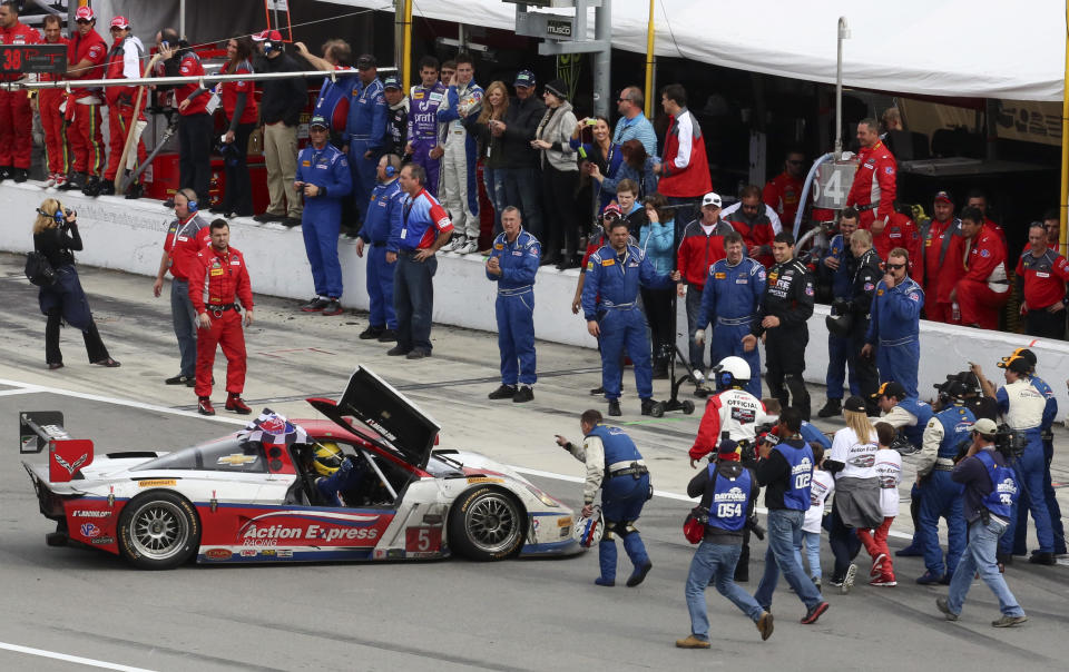 Driver Joao Barbosa, waves the checkered flag from his car as he is surrounded by crew members and photographers after winning the IMSA Series Rolex 24 hour auto race at Daytona International Speedway in Daytona Beach, Fla., Sunday, Jan. 26, 2014.(AP Photo/David Graham)