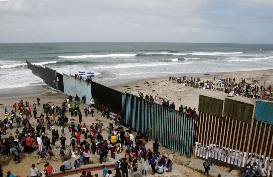 Members of a caravan of migrants from Central America and supporters gather on both sides of the border fence.