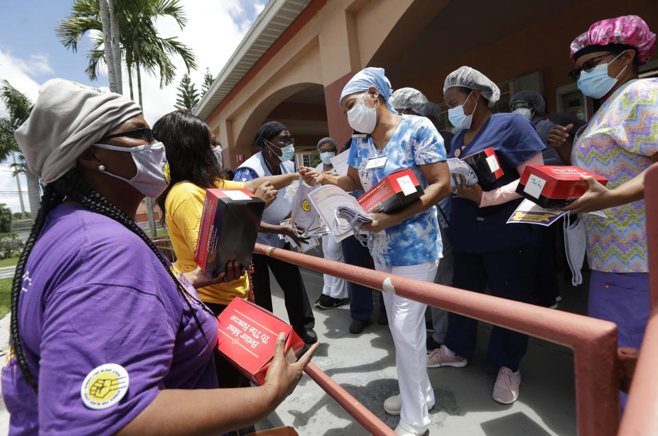 Union members hand out masks to prevent the spread of the new coronavirus and lunches to workers at the Franco Nursing & Rehabilitation Center, Monday, July 20, 2020, in Miami. Most facilities, experts and industry leaders told The Associated Press that a statewide mask mandate would help protect staff members, and consequently residents, from the virus. (AP Photo/Wilfredo Lee)