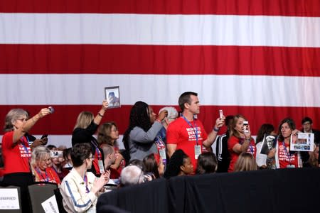 Families of victims of gun violence hold up photos of their loved ones as 2020 Democratic U.S. presidential candidates speak during the Presidential Gun Sense Forum in Des Moines