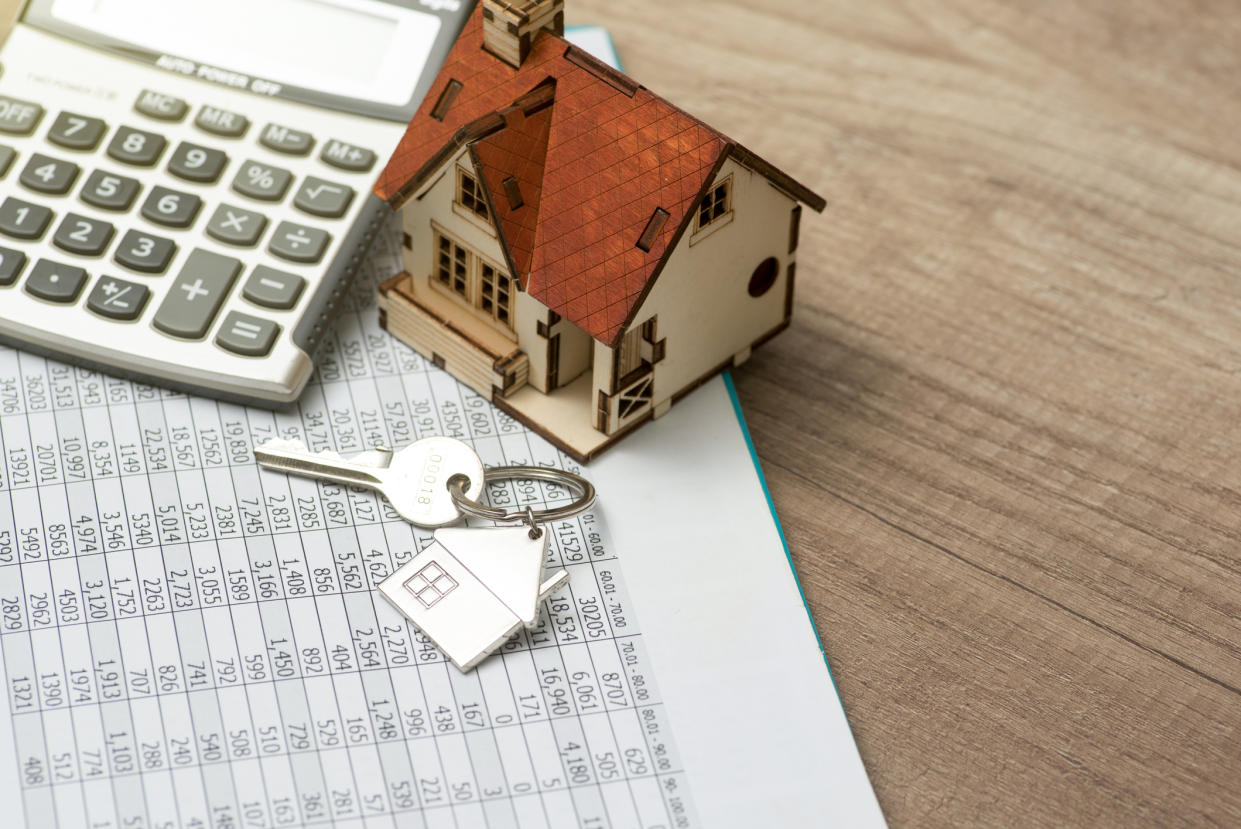  House and house key with calculator and mortgage rates. 