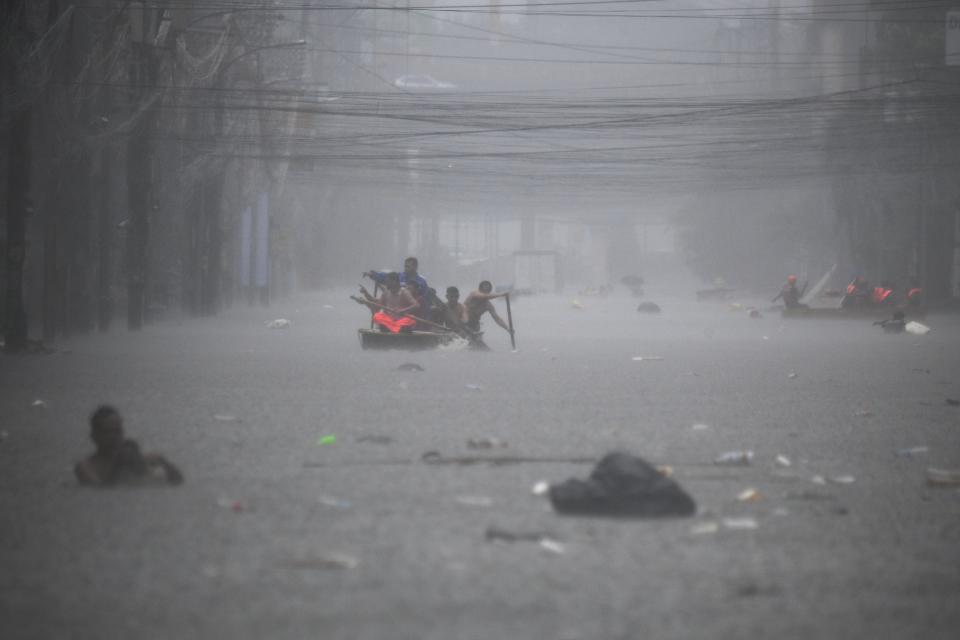 Rescuers paddle their boats along a flooded street in Manila (AFP via Getty Images)