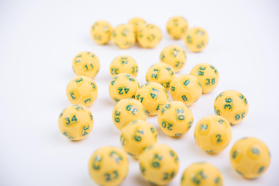 Oz Lotto yellow balls are pictured.