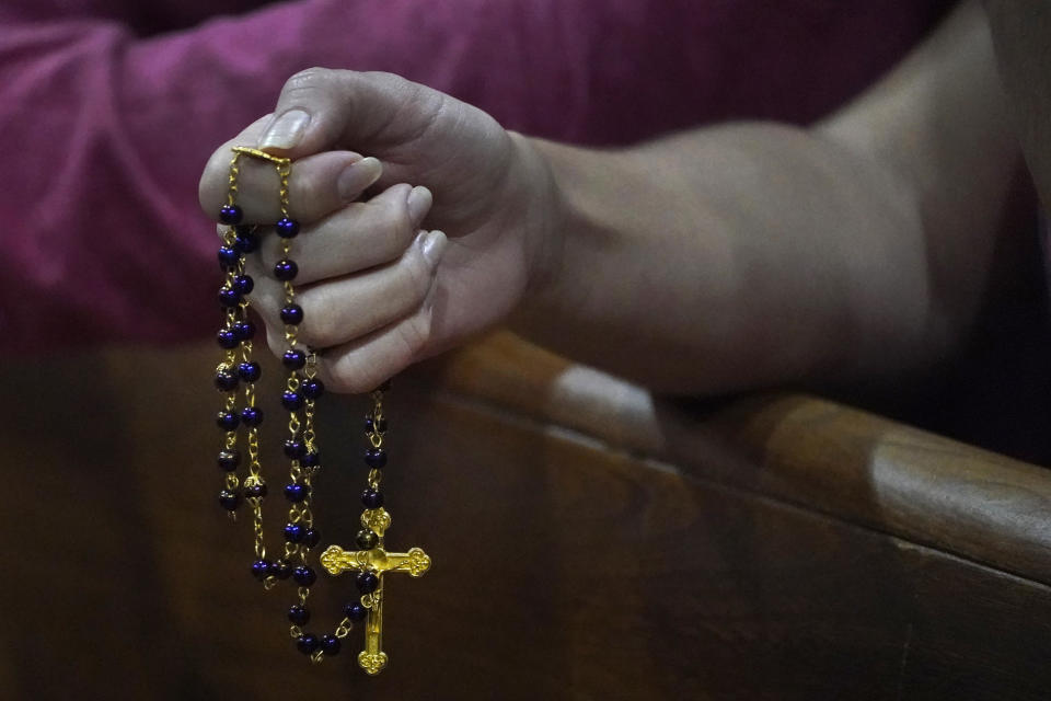 A young woman holds a rosary as she prays, late Saturday, June 26, 2021, during a prayer vigil for the victims and families of the Champlain Towers collapsed building in Surfside, Fla., at the nearby St. Joseph Catholic Church in Miami Beach, Fla. Many people were still unaccounted for two days after Thursday's fatal collapse. (AP Photo/Wilfredo Lee)