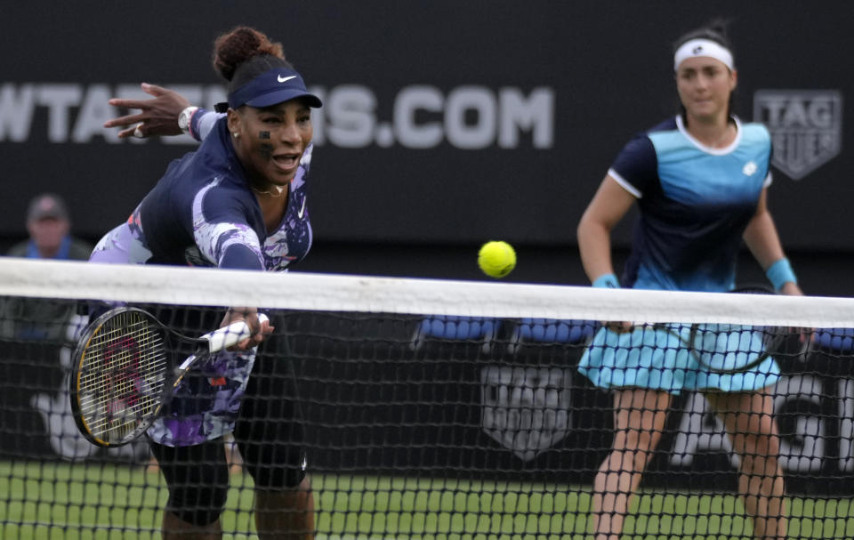 Serena Williams of the United States, left, returns the ball as Ons Jabeur of Tunisia looks on during their doubles tennis match against Marie Bouzkova of Czech Republic and Sara Sorribes Tormo of Spain at the Eastbourne International tennis tournament in Eastbourne, England, Tuesday, June 21, 2022. (AP Photo/Kirsty Wigglesworth)