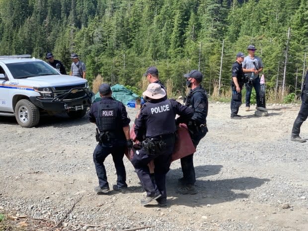 RCMP officers carry a person who was removed from a blockade and arrested at a protest near the Fairy Creek watershed on southern Vancouver Island in August.  (Kathryn Marlow/CBC News - image credit)