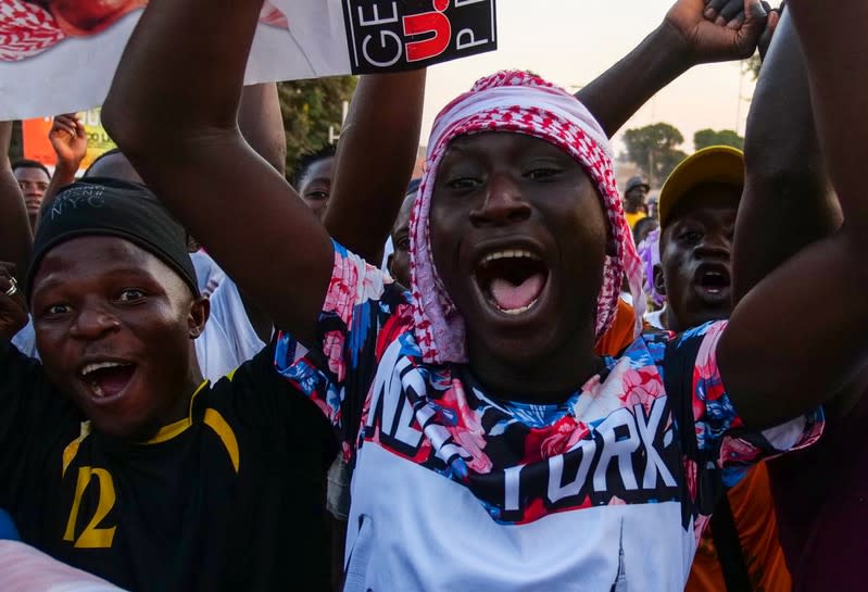 Supporters of presidential candidate Umaro Sissoko Embalo carry his picture and gesture along a road in Bissau