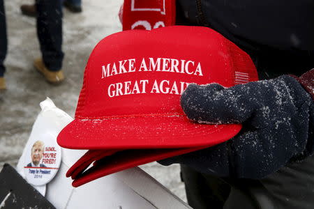 Trump campaign merchandise vendor David Dickson from Florida holds Trump campaign "Make America Great Again" hats dusted with falling snow outside a Trump campaign town hall event in Londonderry, New Hampshire February 8, 2016. REUTERS/Jim Bourg/Files