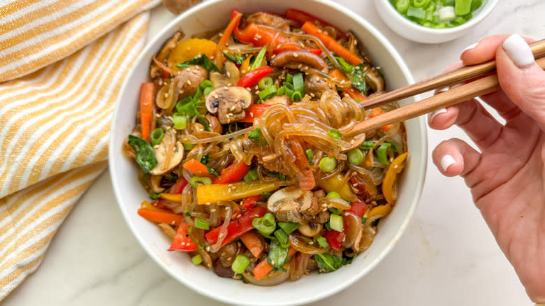 hand with chopsticks in dish