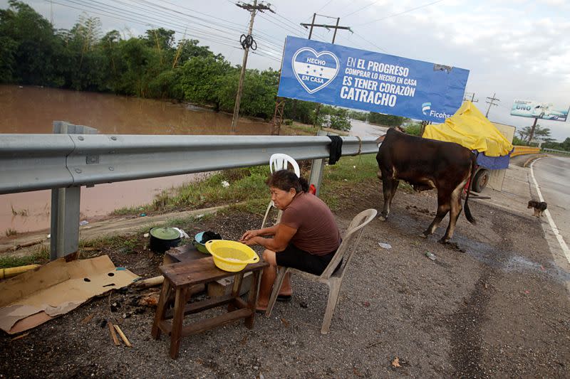 A woman cooks on the side of a highway after losing her home due to heavy rains caused by Hurricane Iota, in El Progreso