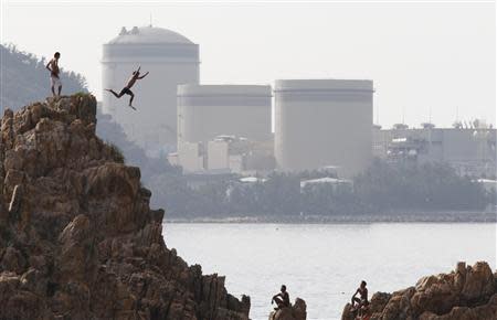 A man on vacation dives into the sea as Kansai Electric Power Co.'s Mihama nuclear power plant is seen in the background in Mihama town, Fukui prefecture, in this file picture taken July 2, 2011. REUTERS/Issei Kato