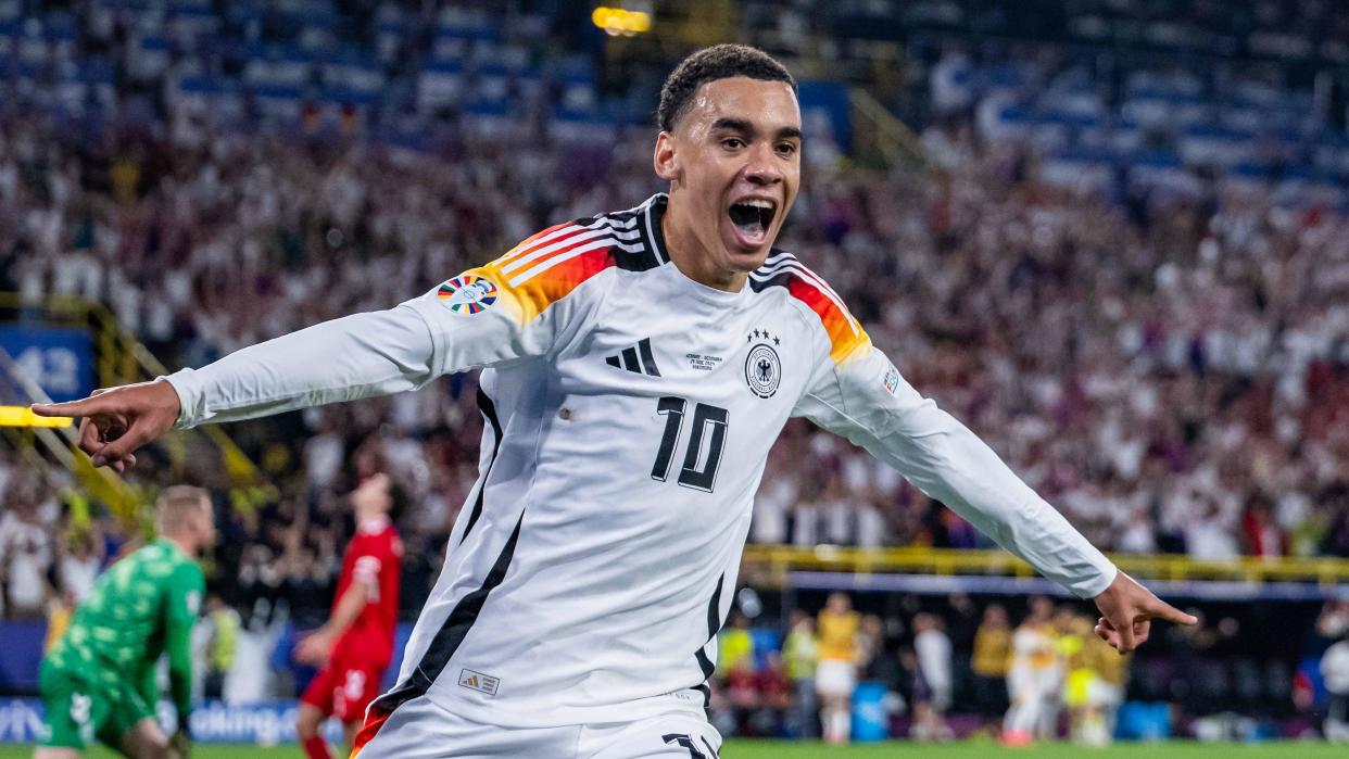 Jamal Musiala wheels away with arms outstretched after scoring for Germany