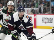 Colorado Avalanche center Nazem Kadri, front, fights for control of the puck with Minnesota Wild right wing Mats Zuccarello in the first period of an NHL hockey game Monday, Jan. 17, 2022, in Denver. (AP Photo/David Zalubowski)