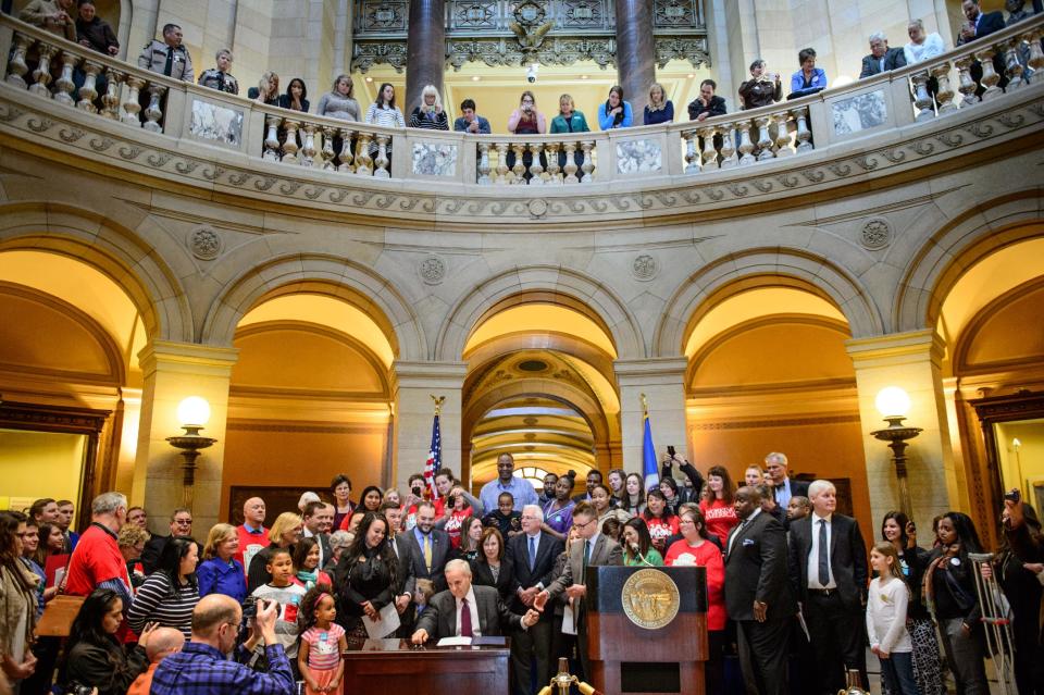 Governor Mark Dayton signes the minimum wage bill into law at a public bill signing ceremony Monday, April 14, 2014 at the Minnesota State Capitol Rotunda in St. Paul. Minnesota goes from having one of the nation's lowest minimums to among the highest. With federal wage legislation stuck in Congress, states are rushing to fill the void. (AP Photo/The Star Tribune, Glen Stubbe) MANDATORY CREDIT; ST. PAUL PIONEER PRESS OUT; MAGS OUT; TWIN CITIES TV OUT