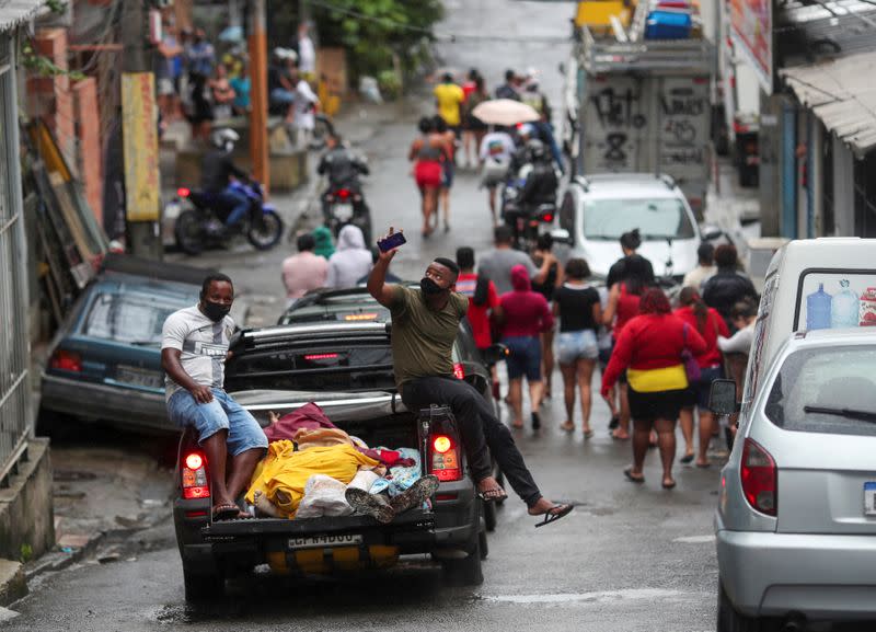 Residents wearing protective masks transport dead bodies after a police operation against drug gangs in Rio de Janeiro