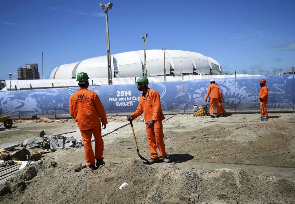 Construction workers prepare a site before putting down bricks under the midday sun next to the Dunas arena soccer stadium in Natal, June 12 , 2014. Mexico will face Cameroon in their 2014 World Cup football match here on June 13. REUTERS/Dylan Martinez