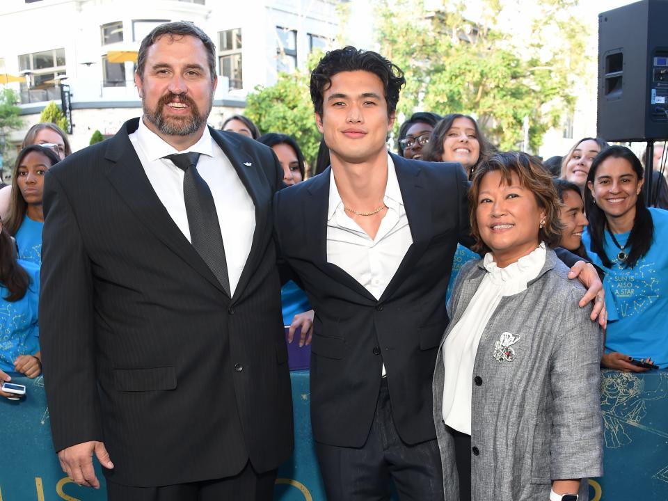 charles melton with his hands around his parents phil (on the left) and sukyong (on the right)