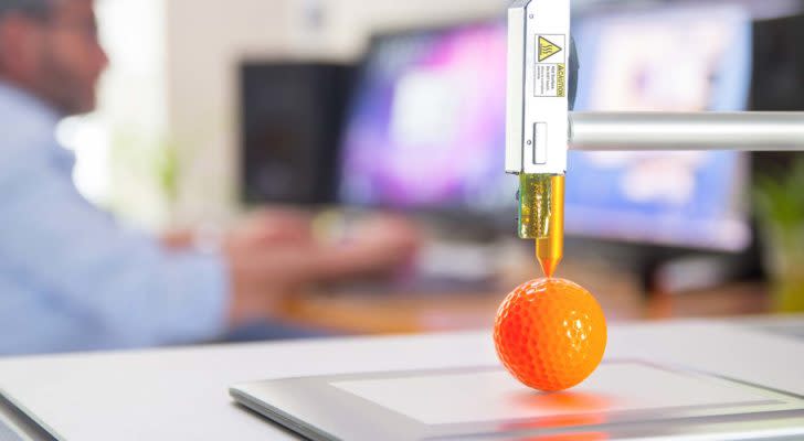 a scientist uses a 3D printer to make an orange golf ball