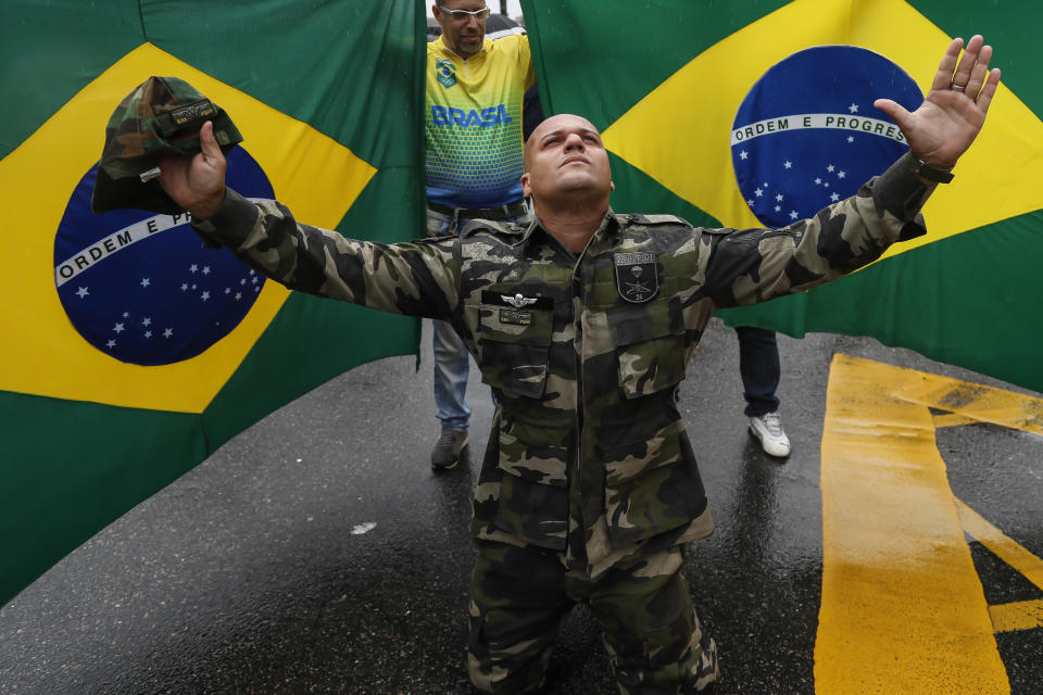 FILE - A supporter of President Jair Bolsonaro dressed in fatigues, kneels with his arms spread out in front of Brazilian national flags, during a protest against his defeat in the presidential runoff election, in Rio de Janeiro, Brazil, Nov. 2, 2022. Thousands of supporters have called on the military to keep the far-right leader in power. (AP Photo/Bruna Prado, File)