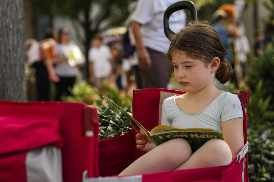 Sarah Tomlinson, 6, reads a book as community members, teachers, parents, students and elected officials protest the closing of Libraries in Houston Independent School District schools outside the Hattie Mae White Educational Service Center on Saturday, Aug. 5, 2023, in Houston. (Raquel Natalicchio/Houston Chronicle via AP)