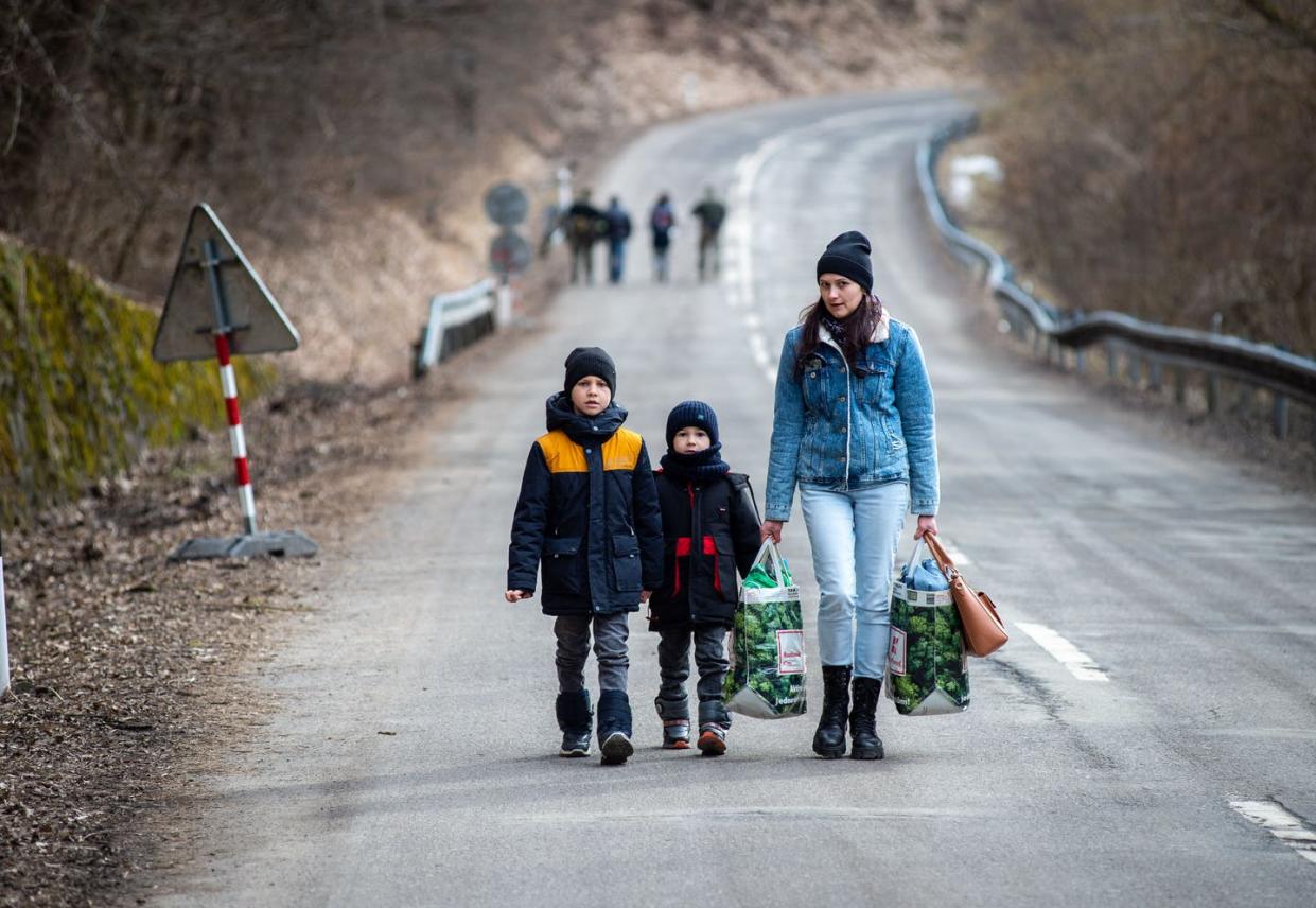 <span class="caption">A Ukrainian family crosses into Slovakia on Feb. 25, 2022. </span> <span class="attribution"><a class="link " href="https://media.gettyimages.com/photos/woman-with-two-children-and-carrying-bags-walk-on-a-street-to-leave-picture-id1238750607?s=2048x2048" rel="nofollow noopener" target="_blank" data-ylk="slk:PETER LAZAR/AFP via Getty Images;elm:context_link;itc:0;sec:content-canvas">PETER LAZAR/AFP via Getty Images</a></span>