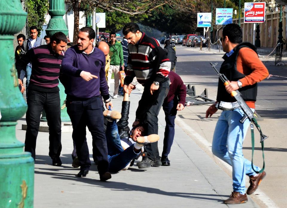 Plainclothes security men drag a student protester injured in clashes between supporters of ousted President Mohammed Morsi and security forces in Alexandria, Egypt, Thursday, Jan. 23, 2014. Hundreds of pro-Morsi students clashed with security forces in fierce street battles in the Mediterranean city early Thursday, leaving one protester dead, according to security officials. (AP Photo/Heba Khamis)