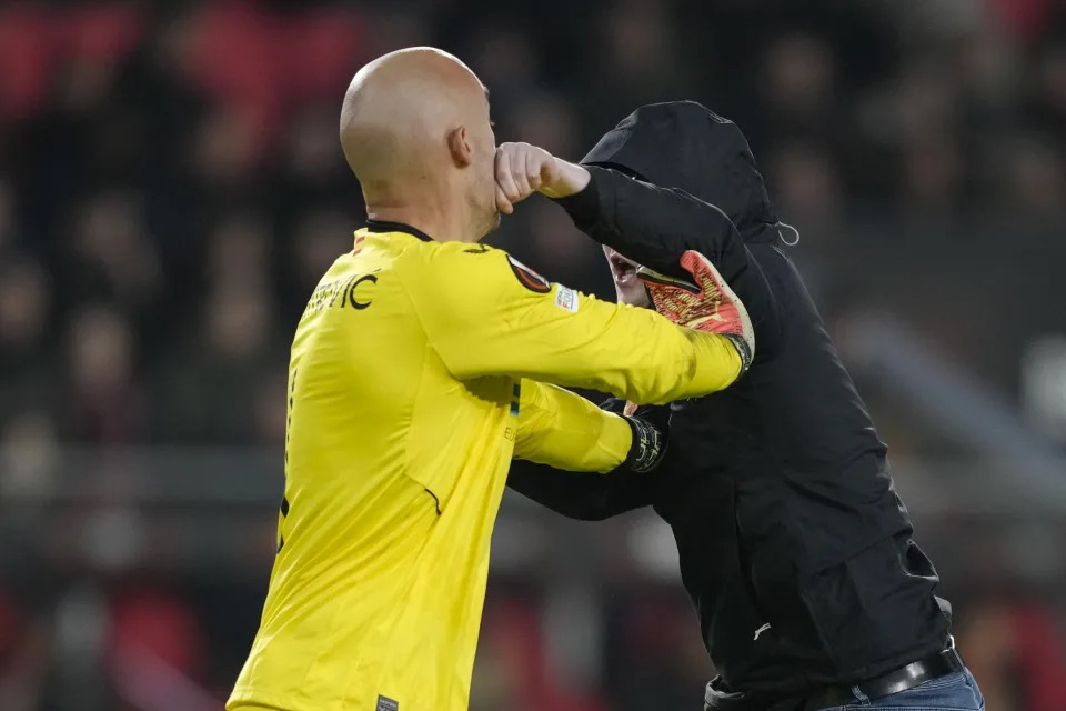 A PSV supporter punches Sevilla's goalkeeper Marko Dmitrovic in the face during the Europa League playoff second leg soccer match between PSV and Sevilla at the Philips stadium in Eindhoven, Netherlands, Thursday, Feb. 23, 2023. Sevilla won 3-2 on aggregate. (AP Photo/Peter Dejong)