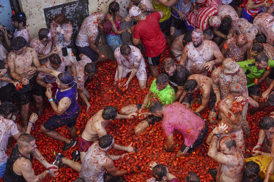 Revellers throw tomatoes at each other during the annual "Tomatina", tomato fight fiesta in the village of Bunol near Valencia, Spain, Wednesday, Aug. 31, 2022. The tomato fight took place once again following a two-year suspension owing to the coronavirus pandemic. (AP Photo/Alberto Saiz)