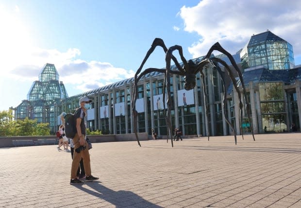 A photographer wearing a mask stands near the statue of Maman outside the National Gallery of Canada in Ottawa on Thursday. On Saturday, health officials in the nation's capital reported 65 new cases of COVID-19.  (Trevor Pritchard/CBC - image credit)