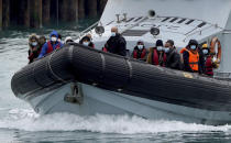 A group of people thought to be migrants are brought in to Dover, Kent, onboard a Border Force vessel following a small boat incident in the Channel, Wednesday, April 13, 2022. Britain's Conservative government has struck a deal with Rwanda to send some asylum-seekers thousands of miles away to the East African country, a move that opposition politicians and refugee groups condemned as inhumane, unworkable and a waste of public money. (Gareth Fuller/PA via AP)