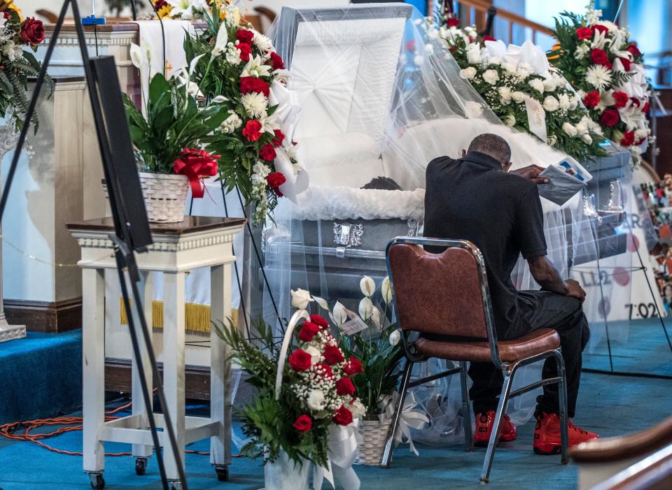 Gregory Wilson wipes away a tear as he sits  with his son Allen, 13, who lay in his coffin at King Solomon Missionary Baptist Church. Wilson was killed by a stray bullet while in his home. July 9, 2022