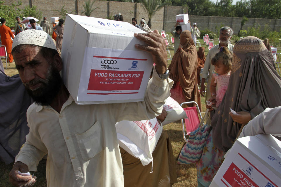 People of flood affected area leave after receiving food and other items distributed by the religious charity group Al-Khidmat Foundation Pakistan, in Shabqadar near Peshawar, Pakistan, Tuesday, Sept. 13, 2022. The death toll from three months of record-breaking floods in Pakistan rose to over 1,400, officials said Tuesday, as the minister for climate warned the prolonged monsoon rains will continue lashing this impoverished nation in the coming weeks. (AP Photo/Muhammad Sajjad)