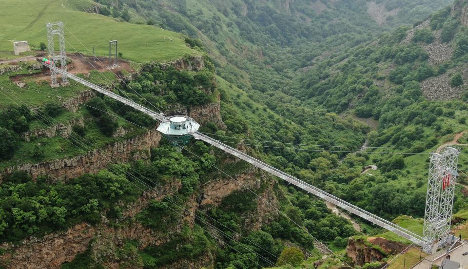 a glass bar suspended in the air in the middle of a glass bridge above Dashbashi Canyon in the country of Georgia