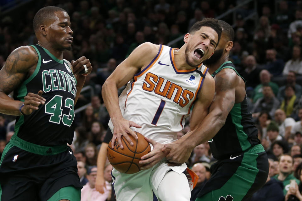 Phoenix Suns guard Devin Booker (1) yells as he drives to the basket between Boston Celtics guard Javonte Green (43) guard Brad Wanamaker (9) during the first half of an NBA basketball game, Saturday, Jan. 18, 2020, in Boston. (AP Photo/Mary Schwalm)