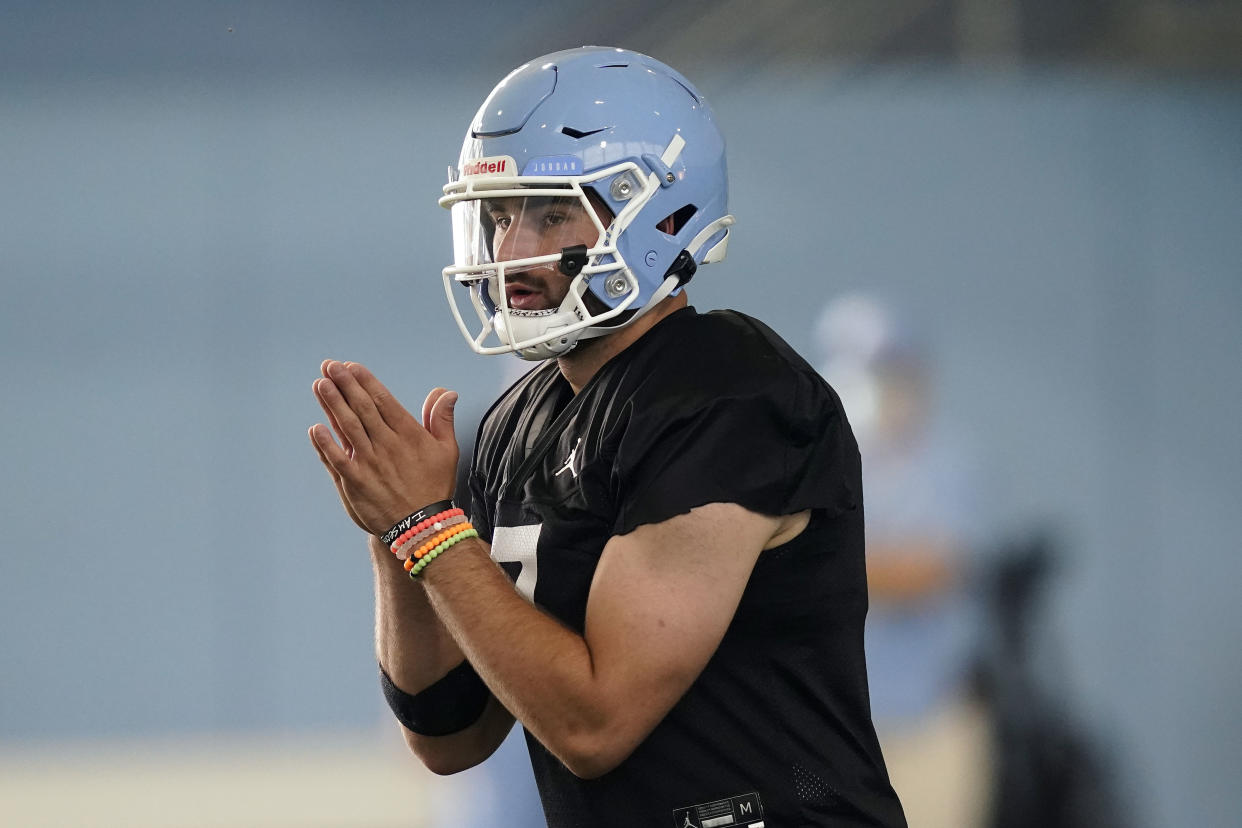 FILE - North Carolina quarterback Sam Howell takes a snap during an NCAA college football practice in Chapel Hill, N.C., in this Thursday, Aug. 5, 2021, file photo. The Tar Heels return 18 starters from an eight-win team and are picked to win the ACC's Coastal Division. (AP Photo/Gerry Broome, File)