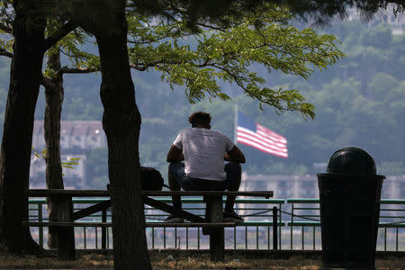 A man sits in the shade at Riverbank State Park during very hot weather in the Washington Heights section of Manhattan in New York City, New York, U.S., June 18, 2018. REUTERS/Mike Segar