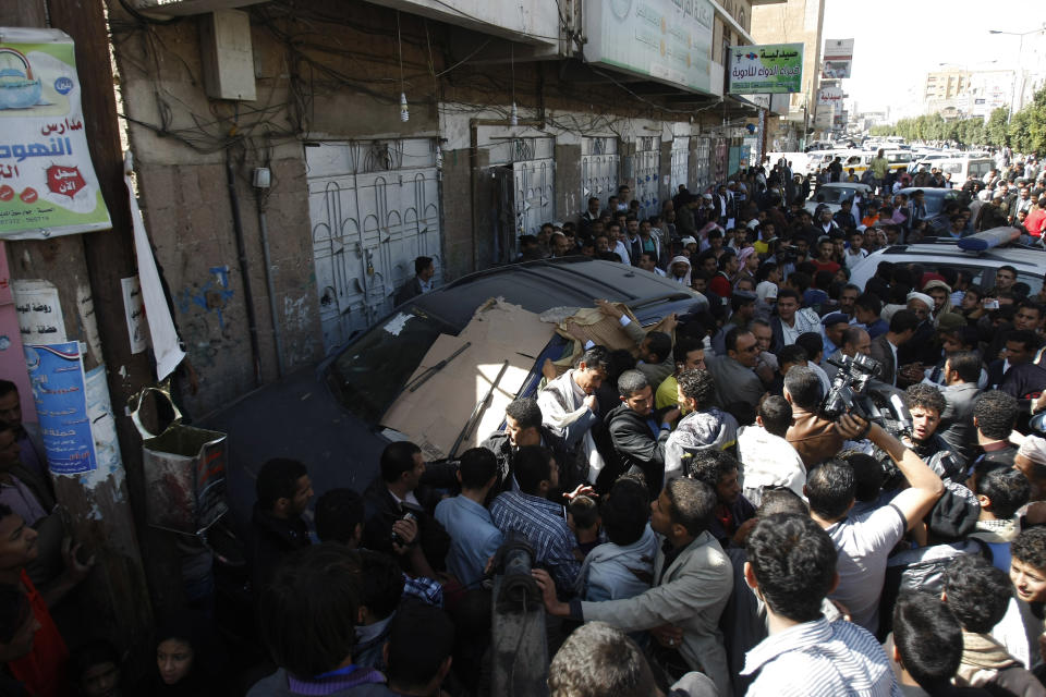 People gather near Ahmed Sharaf Eddin's vehicle, the top envoy of the country's northern rebels after he was shot to death in Sanaa, Yemen, Tuesday, Jan. 21, 2014. Yemeni officials say gunmen assassinated Eddin early Tuesday in his car in the capital, Sanaa. (AP Photo/Hani Mohammed)