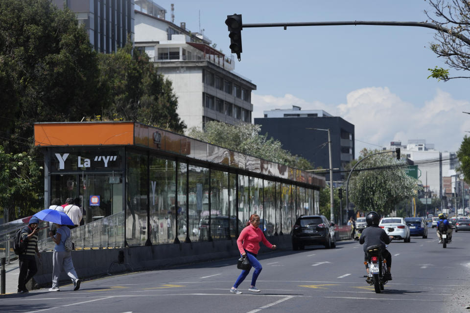 A woman runs across an avenue where traffic lights are not working due to a programed power cut ordered by the ministry of energy, in Quito, Ecuador, Tuesday, April 16, 2024. Ecuador faces electricity rationing due to a prolonged drought and high temperatures that have reduced flows to the main hydroelectric plants. (AP Photo/Dolores Ochoa)