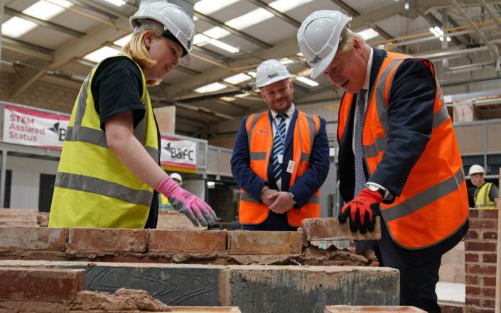 Boris Johnson is pictured taking part in a bricklaying lesson during a visit to Blackpool today - Peter Byrne/AFP