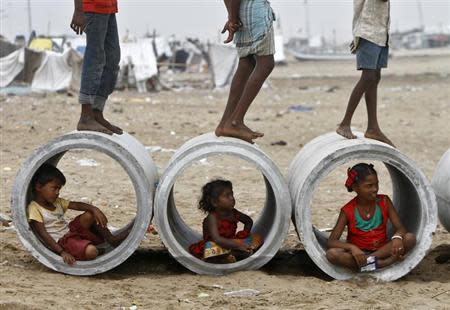 Children sitting inside cement water pipes play on the Marina beach in Chennai October 10, 2013. REUTERS/Babu/Files