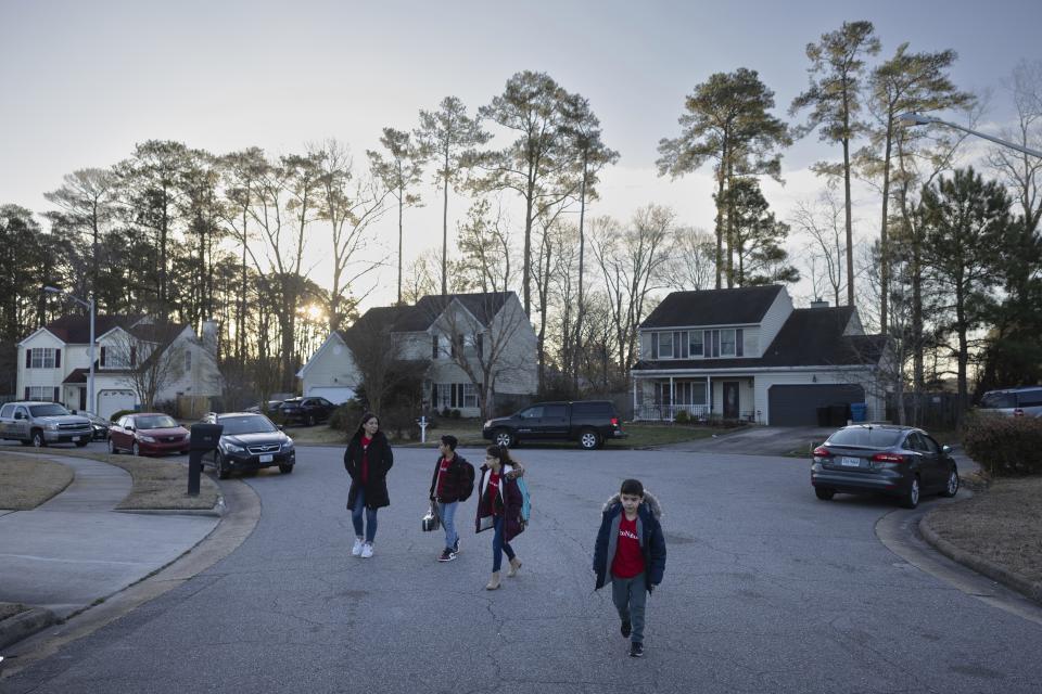 Liz Hurtado, left, walks her children to the bus stop, Tuesday, Feb. 6, 2024, in Virginia Beach, Va. Hurtado, an advocate for Moms Clean Air Force, is pushing for electric school busses in communities with high rates of air pollution. (AP Photo/Tom Brenner)