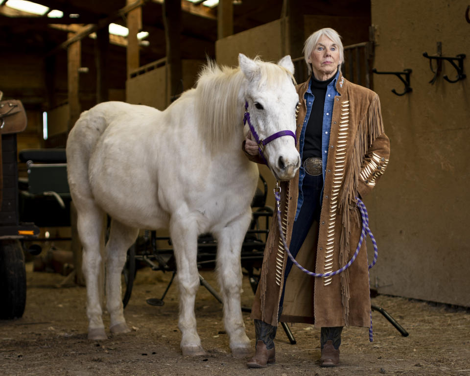 Jonnie Jonckowski poses for a portrait with her horse Sunny in the barn at Angel Horses in Billings, Mont., Monday, Dec. 4, 2023. Jonckowski is a Hall of Fame, two-time champion bull-riding pioneer. She began as a hurdler from a Division III school in Montana with a real shot at the big time. Jonckowski made the 1976 U.S. Olympic Trials and had high hopes of making the Olympic Games in Montreal. (AP Photo Mike Clark)