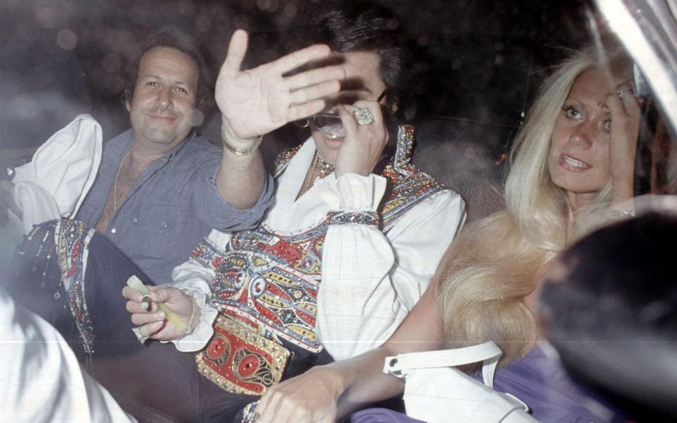 Elvis Presley, girlfriend Diane Goodman and Elvis's road manager Joe Esposito leaving the Hilton Garden Inn at JFK Airport for a concert in Uniondale on July 19 1975 - Ron Galella/WireImage