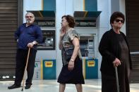 People in Athens on July 29, 2015, stand near empty ATMs belonging to Greece's National Bank