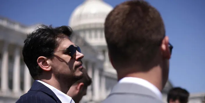 Milo Yiannopoulos watches as Republican Rep. Marjorie Taylor Greene of Georgia at a press conference outside the Capitol on April 28, 2022.