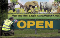 Gary Gilmour wipes an entrance sign to Blair Drummond Safari Park near Stirling, Scotland, Sunday June 28, 2020, where staff are preparing to open the attraction on June 29. Animal parks are set to open along with some other businesses, as part of Scotland's phased release of the coronavirus pandemic lockdown. (Andrew Milligan/PA via AP)