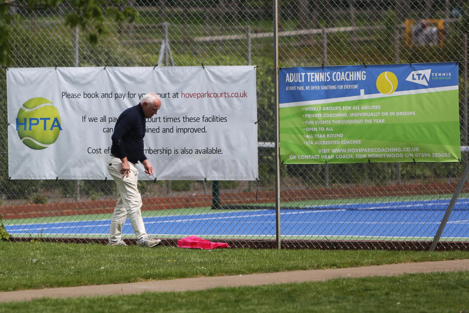 A man prepares for the reopening of tennis courts in Hove Park, near Brighton, as the UK continues in lockdown to curb the spread of Coronavirus during the pandemic.