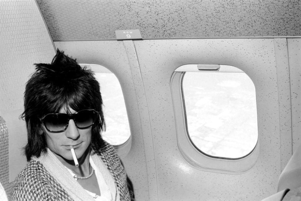 <p>Ronnie Wood smokes a cigarette while onboard a plane during the Rod Stewart and the Faces' American tour in 1975.</p>