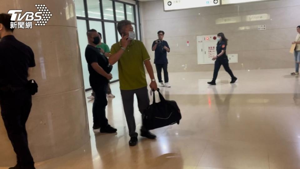 綠色衣服者提著黑色行李袋，裝著700萬千元現鈔來到法院。（圖／潘千詩攝）